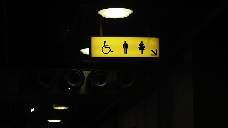 Illuminated Yellow Restroom Sign with Accessibility Symbols