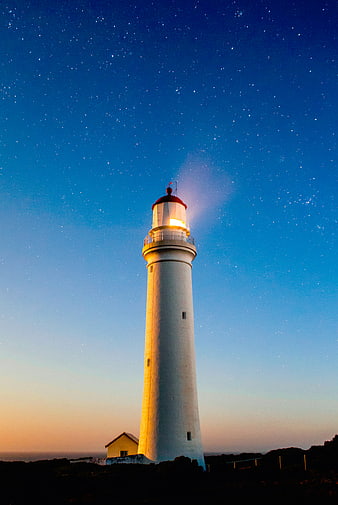 Lighthouse Illuminated Against Starry Night Sky