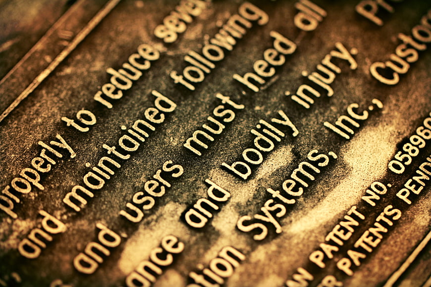 Close-up of engraved warning text on rusty metal plate
