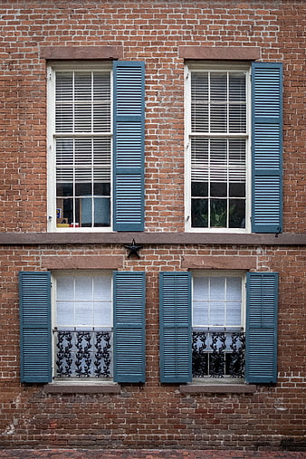 Red brick building facade with blue shutters and windows