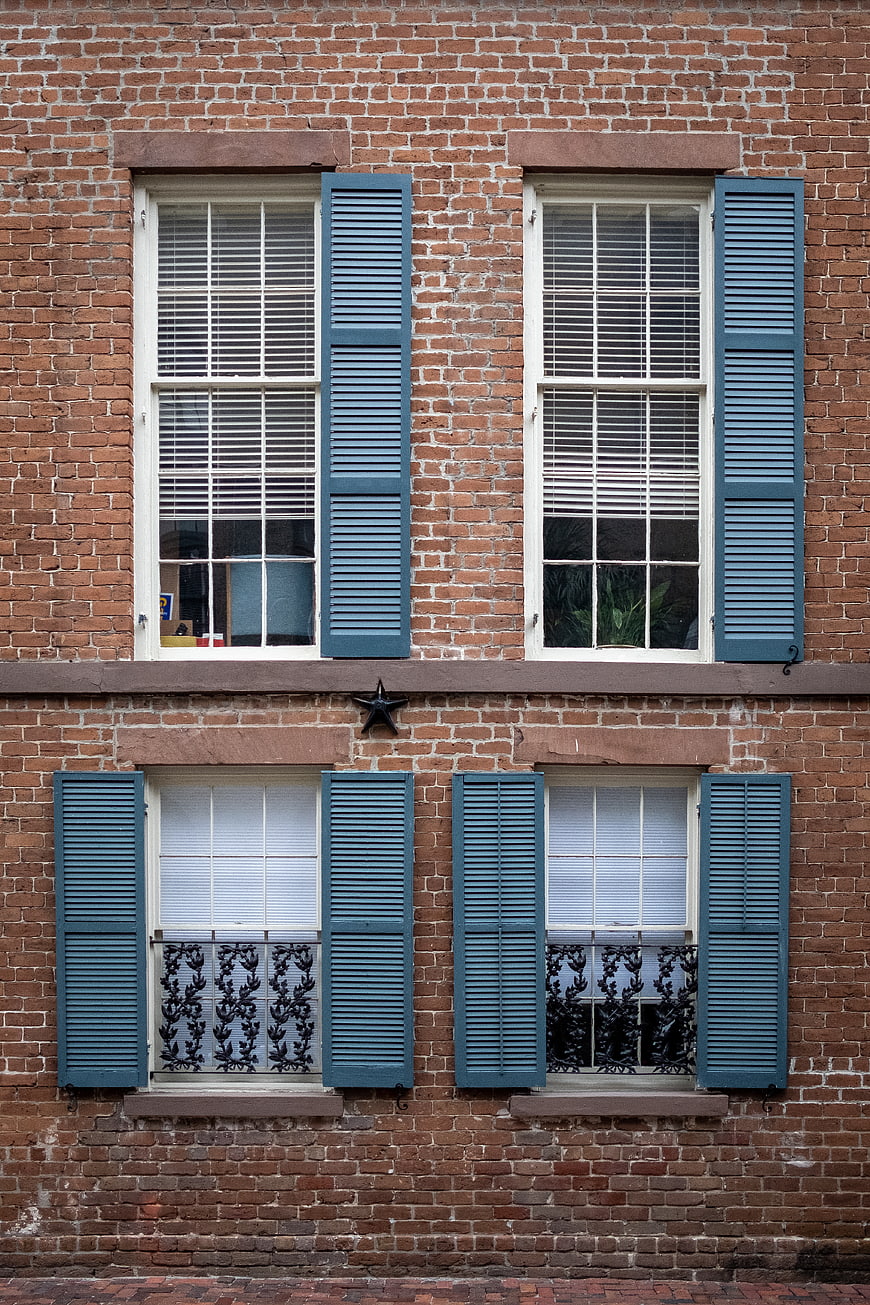 Red brick building facade with blue shutters and windows