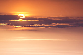 Vibrant orange sunset with sun partially obscured by clouds
