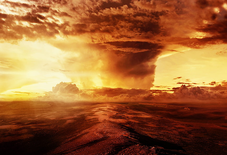 Dramatic fiery sunset over a wet, textured landscape with towering storm clouds
