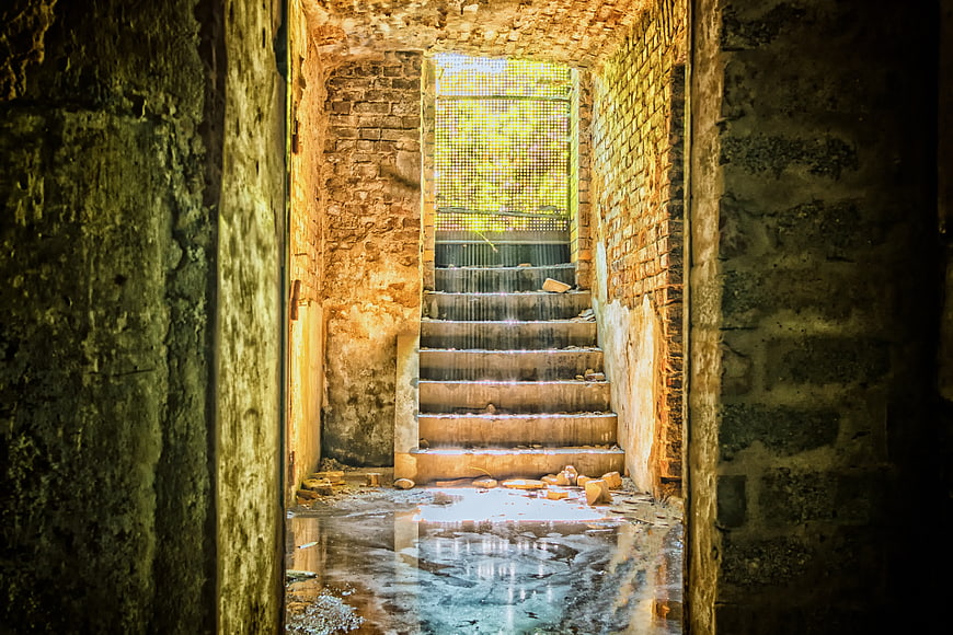 Abandoned Staircase with Sunlight and Puddle Reflection