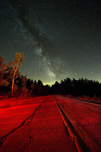 Milky Way over cracked road with red light at night