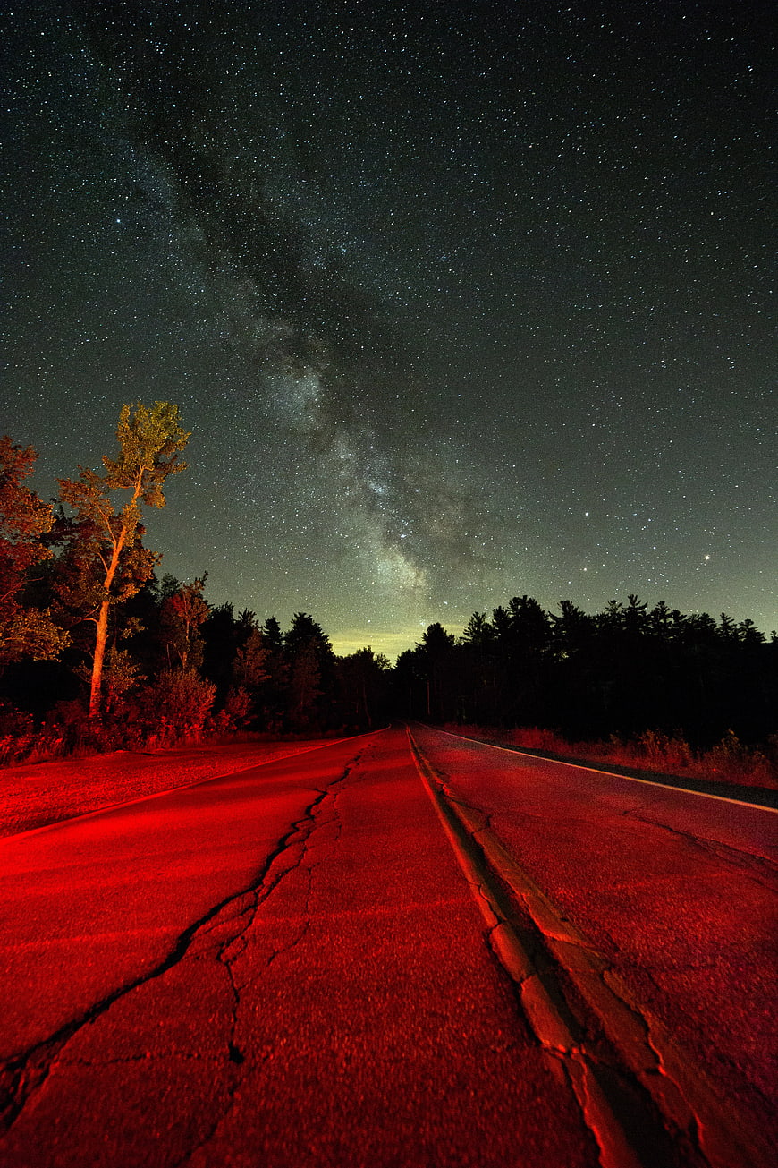 Milky Way over cracked road with red light at night