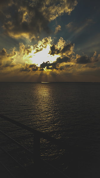 Dramatic sunset over ocean with sun rays through clouds