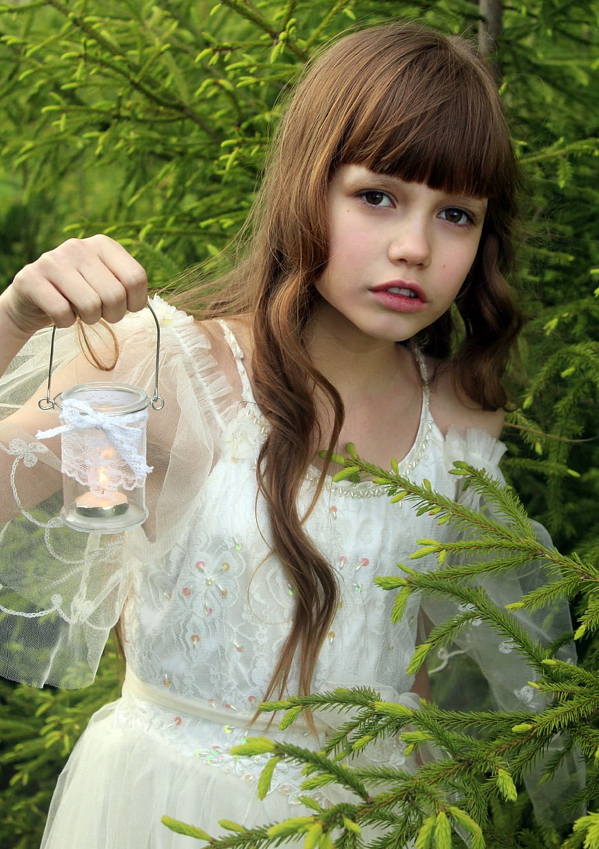 Young Girl in White Dress Holding Lantern in Forest