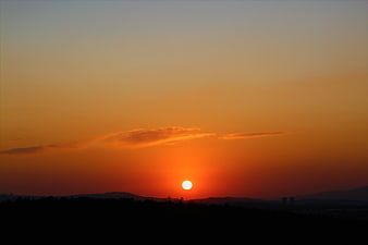 Vibrant orange sunset over dark silhouette landscape
