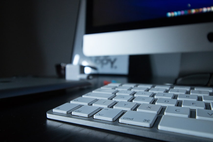 Close-up of Apple Keyboard and iMac on Dark Desk
