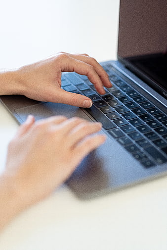 Close-up of hands typing on a laptop keyboard