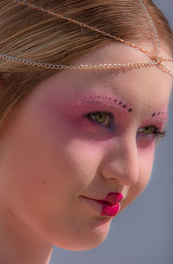 Close-up of woman with pink fantasy makeup and gold chain headpiece