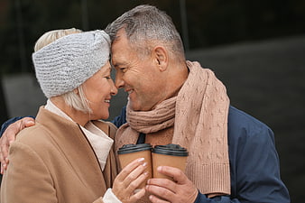 Happy Senior Couple Sharing Coffee Outdoors in Winter