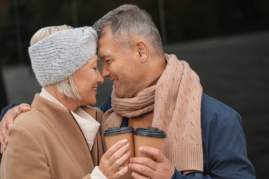 Happy Senior Couple Sharing Coffee Outdoors in Winter