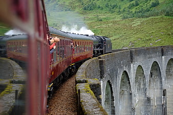 Red Steam Train Crossing Historic Stone Viaduct In Green Countryside