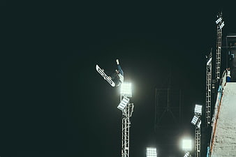 Snowboarder performing aerial trick at night under stadium lights