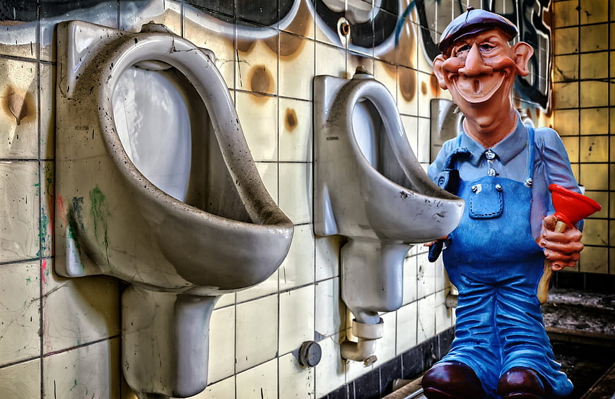 Plumber Statue in Dirty Public Restroom with Urinals