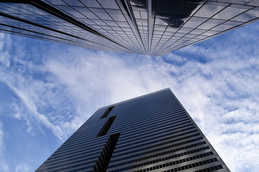 Low angle view of modern glass skyscrapers against blue sky