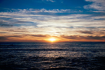Dramatic Sunset Over Ocean with Golden Sunlight and Clouds