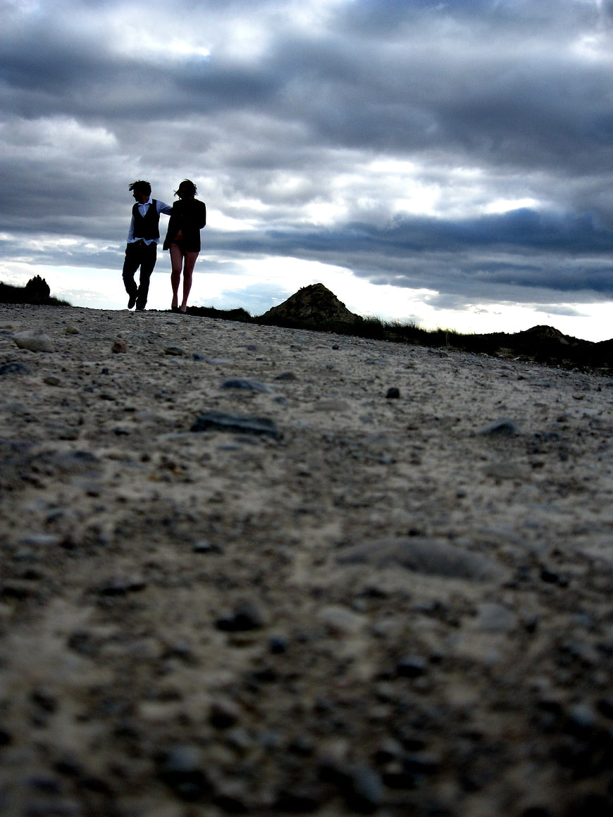 Silhouette of a couple walking on a rocky beach under a dramatic cloudy sky