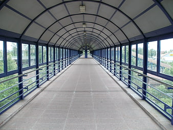 Empty blue arched pedestrian bridge with glass windows