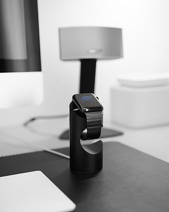 Black smartwatch on minimalist stand in monochrome