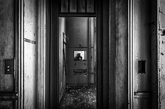 Black and white photo of abandoned building interior with man in mirror