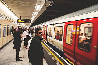 Man Waiting On London Underground Platform With Moving Red Train