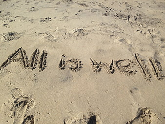 Handwritten phrase all is well carved into sandy beach surface