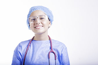 Smiling female surgeon in blue scrubs and safety glasses