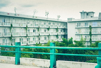 Modern white apartment complex with green railing foreground