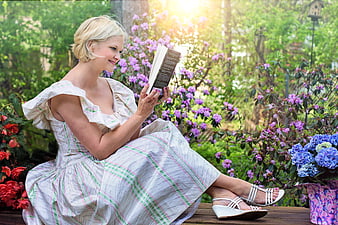 Happy blonde woman reading book in garden