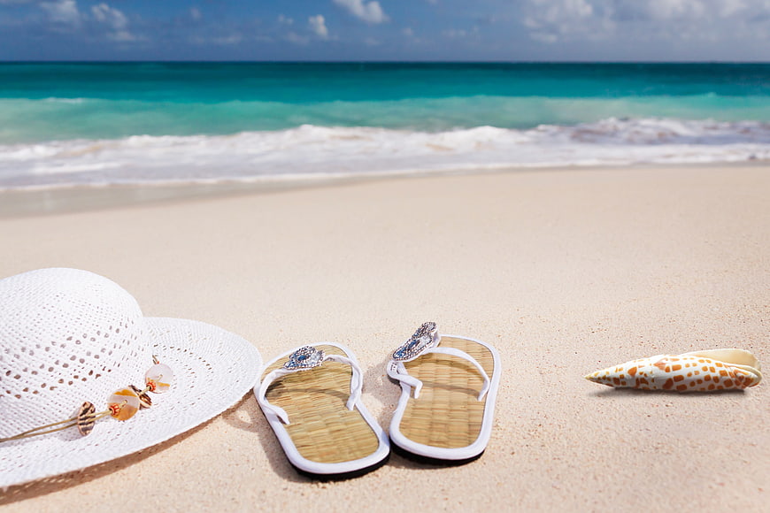 White Hat and Flip-Flops on Tropical Beach Sand