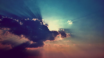 Dramatic sunset sky with sun rays breaking through dark clouds