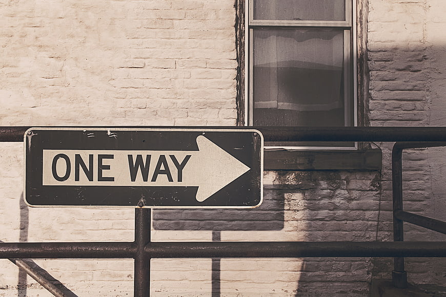 Vintage One Way Street Sign on White Brick Wall
