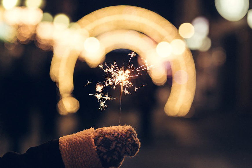 Hand Holding Sparkler with Bokeh Rainbow at Night