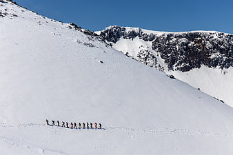 Group of hikers ascending snowy Mount Adatara in winter