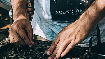 Close-up of DJ hands mixing on audio controller