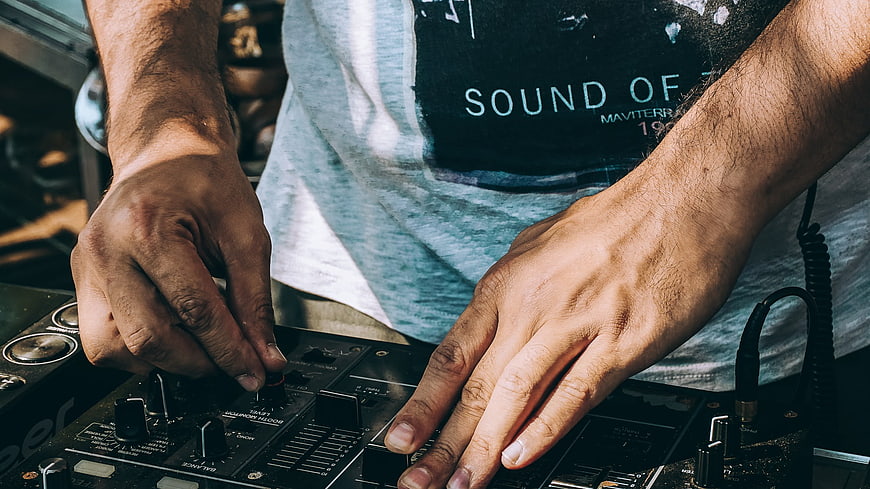 Close-up of DJ hands mixing on audio controller
