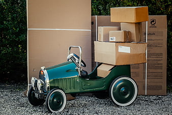 Vintage green pedal car loaded with cardboard moving boxes