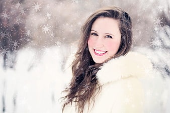 Smiling woman in white fur coat with snowflakes