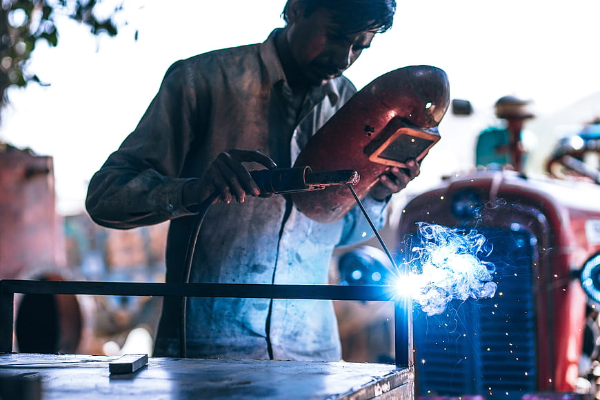 Welder working with sparks in industrial workshop