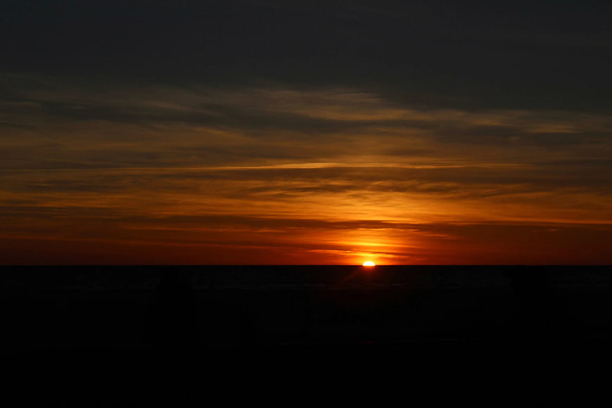 Dramatic Orange Sunset Over Dark Ocean Horizon