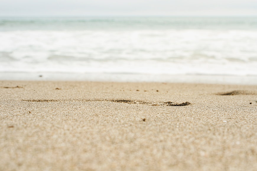Close-up of sandy beach with blurred ocean waves background