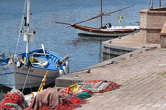 Fishing boats docked at a sunny harbor with nets