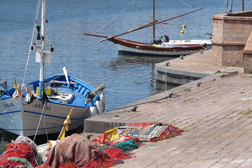 Fishing boats docked at a sunny harbor with nets