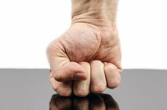 Close-up of clenched fist on reflective surface