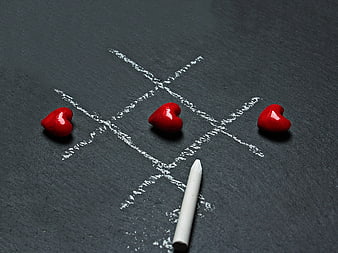 Red hearts winning tic-tac-toe game on black slate