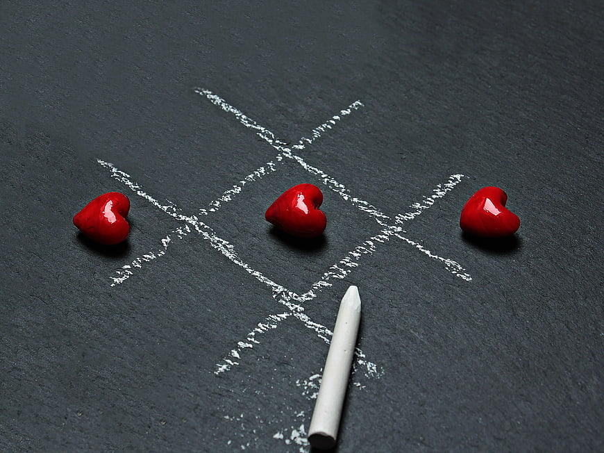 Red hearts winning tic-tac-toe game on black slate