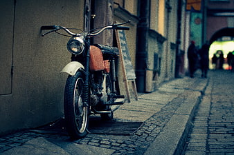 Vintage motorcycle parked on cobblestone street in European city